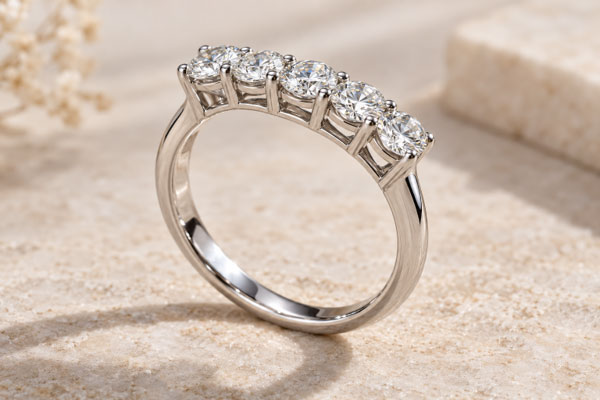 A close-up of a five-stone ring, showing the claw settings, open gallery and smooth band.